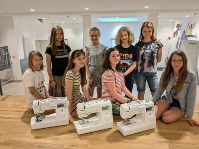 Eine Gruppe Schülerinnen mit drei Nähmaschinen