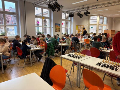 Schüler sitzen an verschiedenen Tischen und spielen Schach