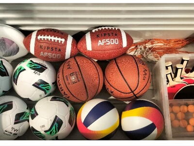 Verschiedene Bälle und Tischtennisschläger liegen in einer Ballkiste